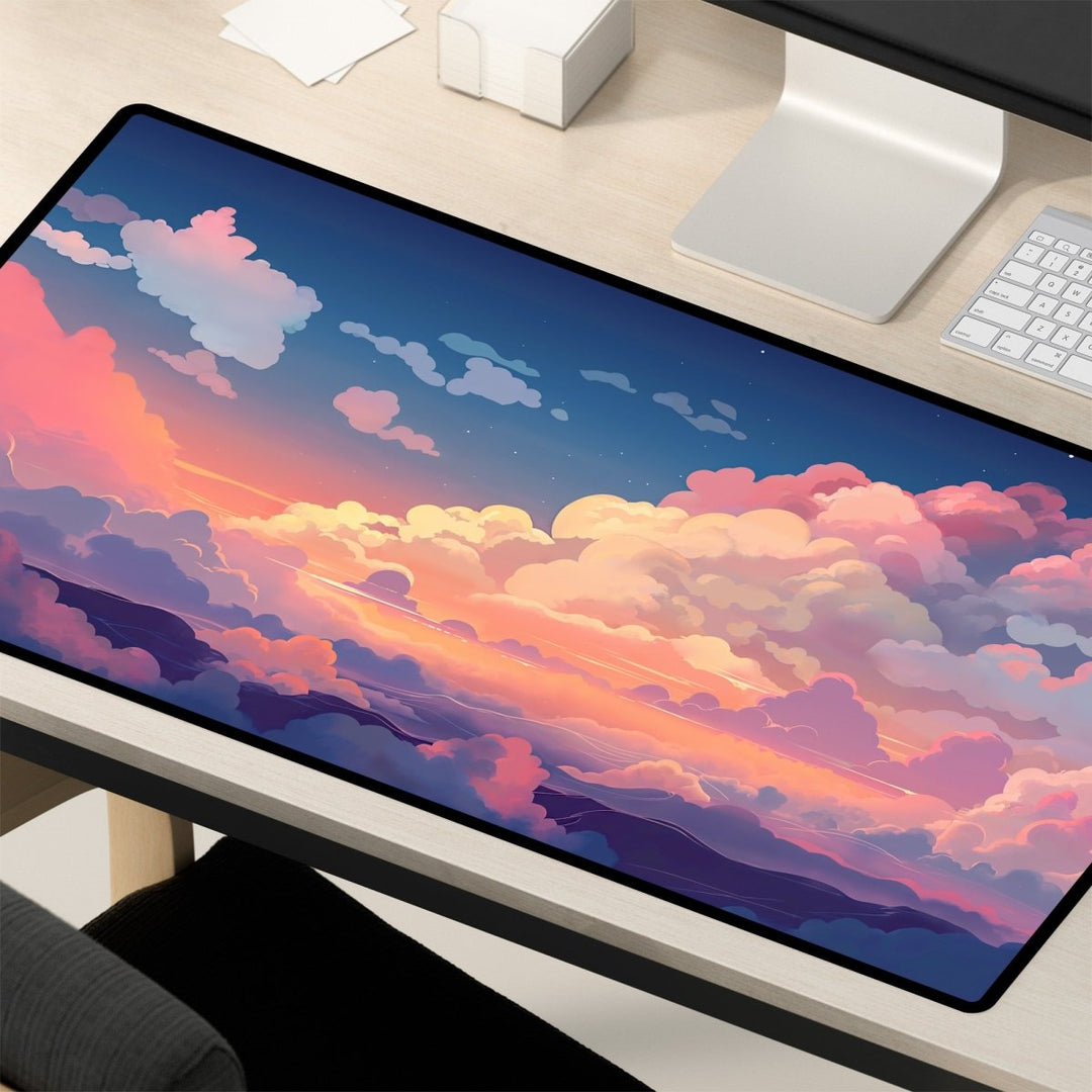 Home Decor - A Cloud Desk Mat – Cute Large Mouse Pad for Gaming & Office Setup with a vibrant digital illustration of a colorful sunset sky with clouds is placed on a wooden desk. Nearby are a computer monitor, keyboard, and some stationery items, including a pen and a note. This kawaii desk decor adds charm to your workspace. - Kaladyn Designs