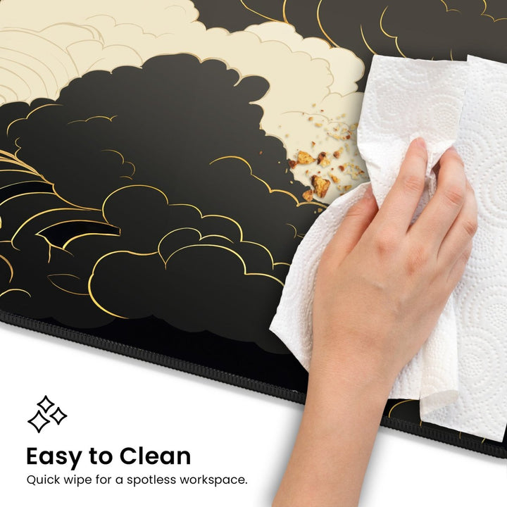 Home Decor - A hand holding a paper towel cleans crumbs off a Dark Cloud Desk Mat – Celestial Gaming Mouse Pad with an intricate design. Text reads, "Easy to Clean: Quick wipe for a spotless workspace. - Kaladyn Designs
