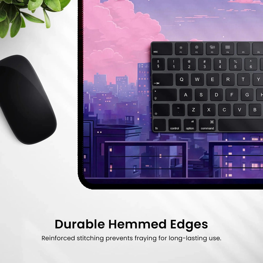 A black computer mouse and keyboard are positioned on a Kawaii Desk Mat – Lofi Vaporwave Pixel Art Anime Mouse Pad for Gaming & Work, which features a purple cityscape design at dusk. Below the mat, text reads, "Durable Hemmed Edges: Reinforced stitching prevents fraying for long-lasting use." A green plant is partially visible in the top left corner, enhancing the lofi vaporwave vibe.