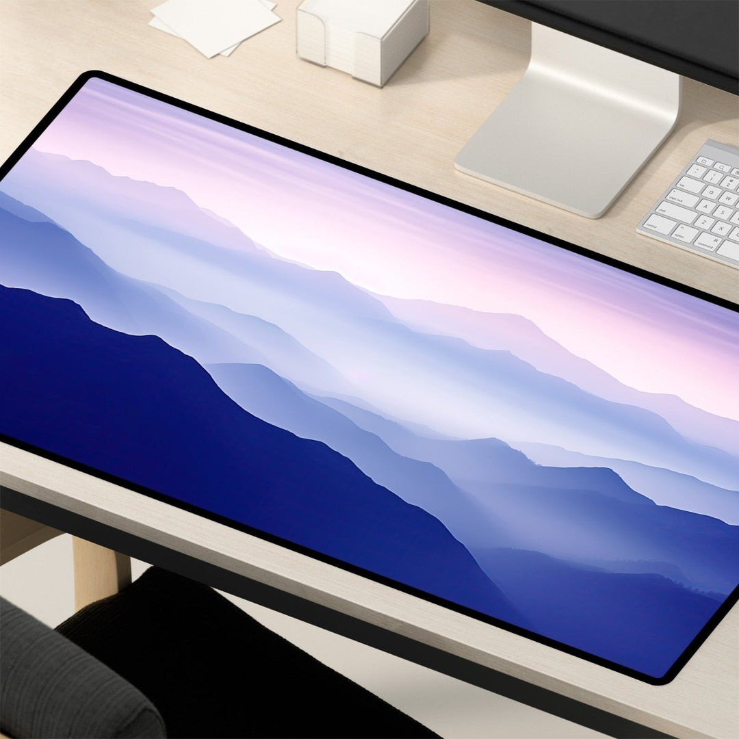 Home Decor - A desk with a large Mountain Desk Mat – Large Nature Mouse Pad for Office or Gaming Setup, featuring a serene mountain range design in varying shades of blue and purple. The desk also holds a monitor, keyboard, papers, and a tissue box. - Kaladyn Designs