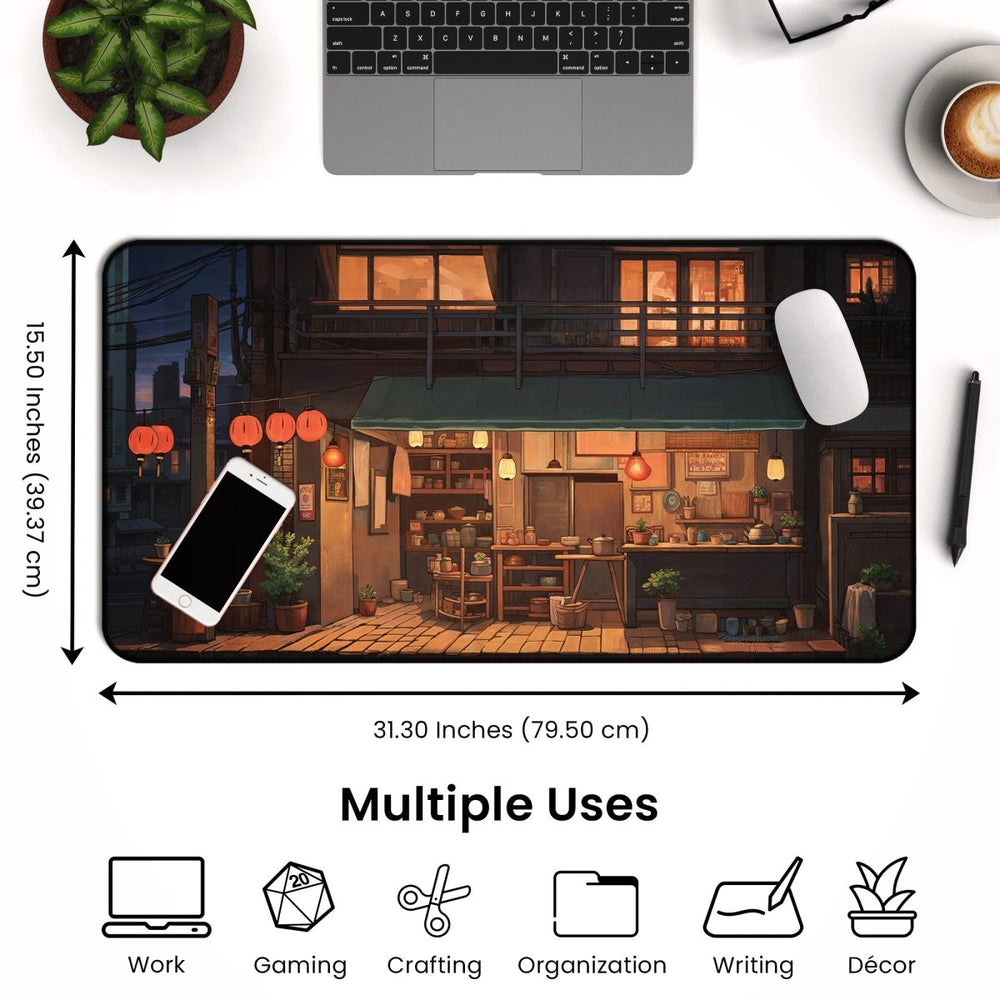 Home Decor - A desktop setup featuring the Anime Shop Desk Mat, a large mouse pad with dimensions of 31.30 inches (79.50 cm) wide and 15.50 inches (39.37 cm) tall, detailed with a street scene in a lofi aesthetic design. Annotations below highlight its uses: work, gaming, crafting, organization, writing, and décor. - Kaladyn Designs