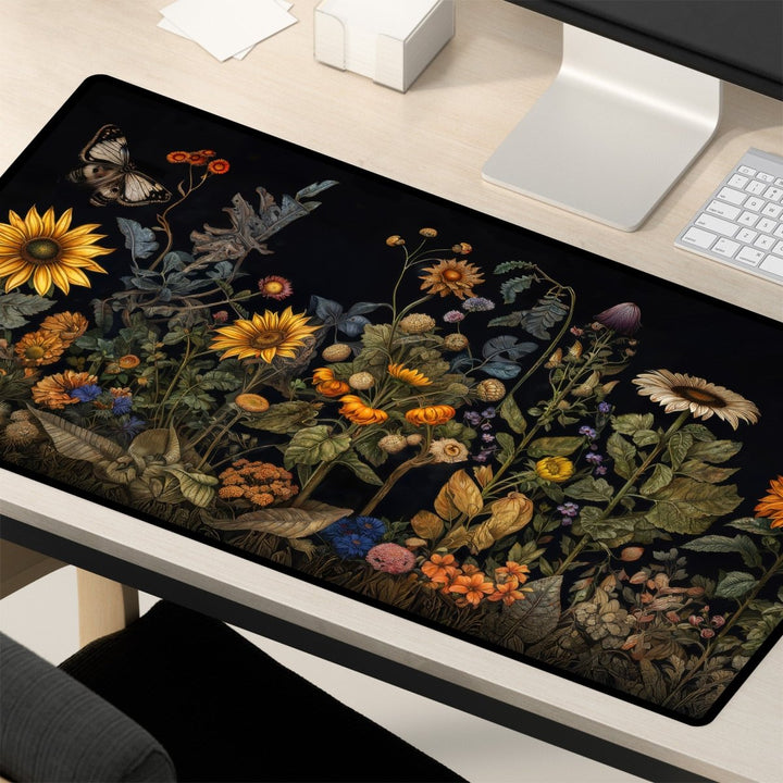 Home Decor - A computer desk is adorned with a Botanical Desk Mat – Vintage Floral Design Large Mouse Pad for Office & Gaming, showcasing an intricate vintage floral design. The mouse pad features a variety of colorful flowers, green foliage, and a butterfly. Nearby are a silver computer monitor, a white keyboard, and some papers. - Kaladyn Designs