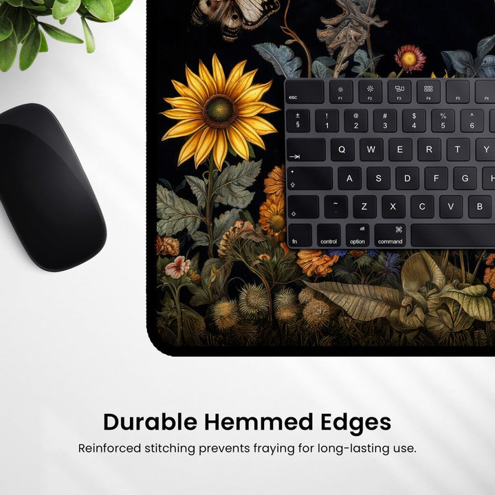 Home Decor - A mouse and keyboard are placed on the Botanical Desk Mat – Vintage Floral Design Large Mouse Pad for Office & Gaming, which features a black background with a vintage floral pattern. The text at the bottom reads, "Durable Hemmed Edges. Reinforced stitching prevents fraying for long - lasting use. - Kaladyn Designs