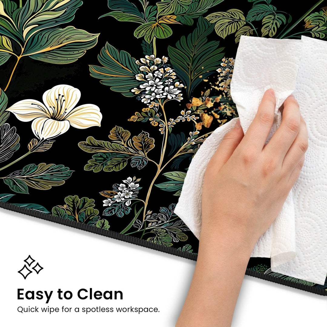 Home Decor - A hand uses a paper towel to wipe crumbs off an Elegant Botanical Black Floral Desk Mat. Text reads, "Easy to Clean - Quick wipe for a spotless workspace. - Kaladyn Designs