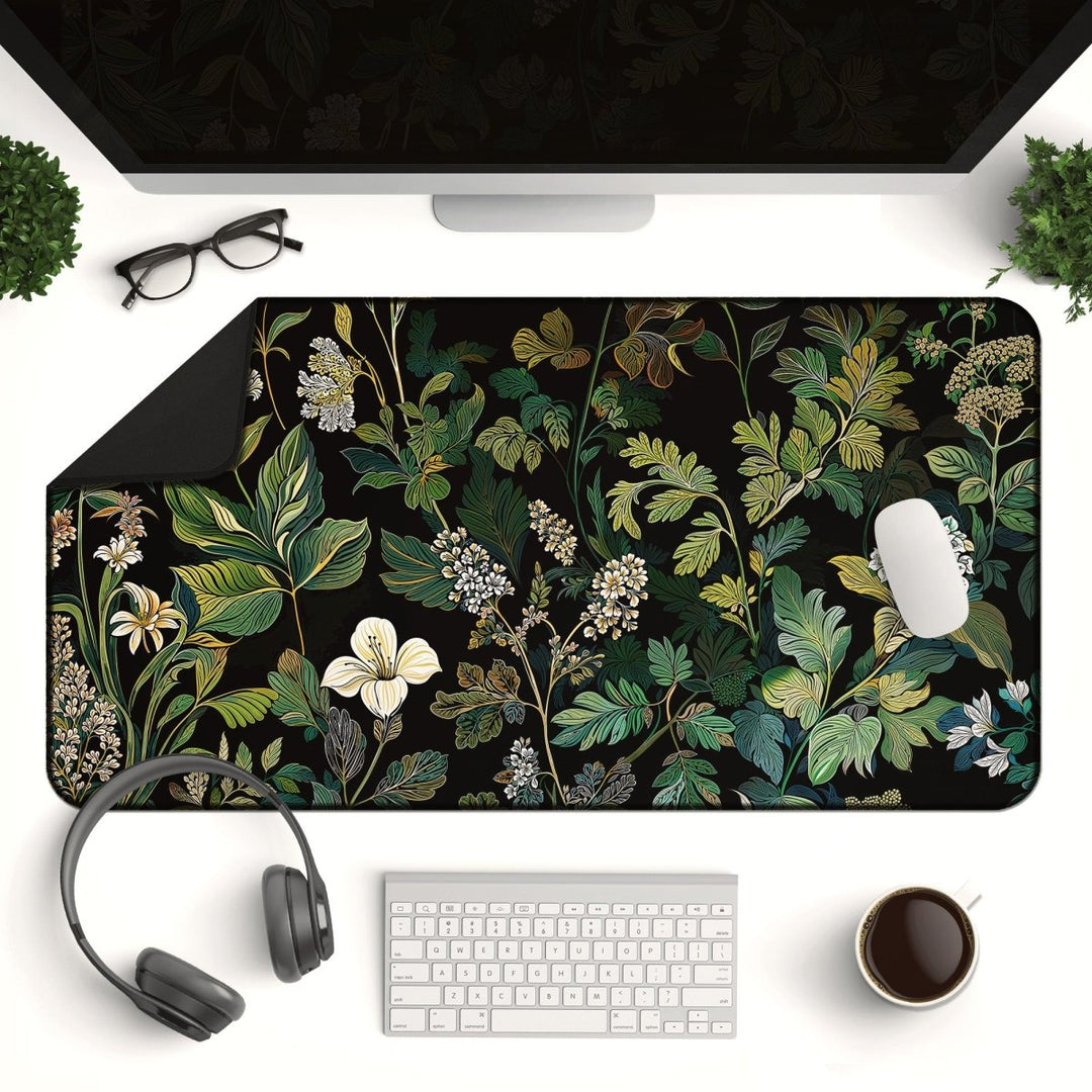 Home Decor - An Elegant Botanical Black Floral Desk Mat featuring a design of green, white, and yellow leaves and flowers on a black background. The mat is complemented by a white mouse, keyboard, headphones, coffee cup, glasses, and a monitor on the sleek white desk. - Kaladyn Designs