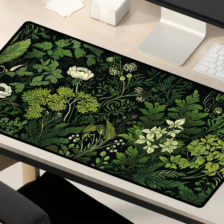 Home Decor - A light wooden computer desk is adorned with a Floral Sage Green Botanical Desk Mat, showcasing intricate green leaves and white flowers. The workspace includes a keyboard, monitor, and a white pencil holder. - Kaladyn Designs