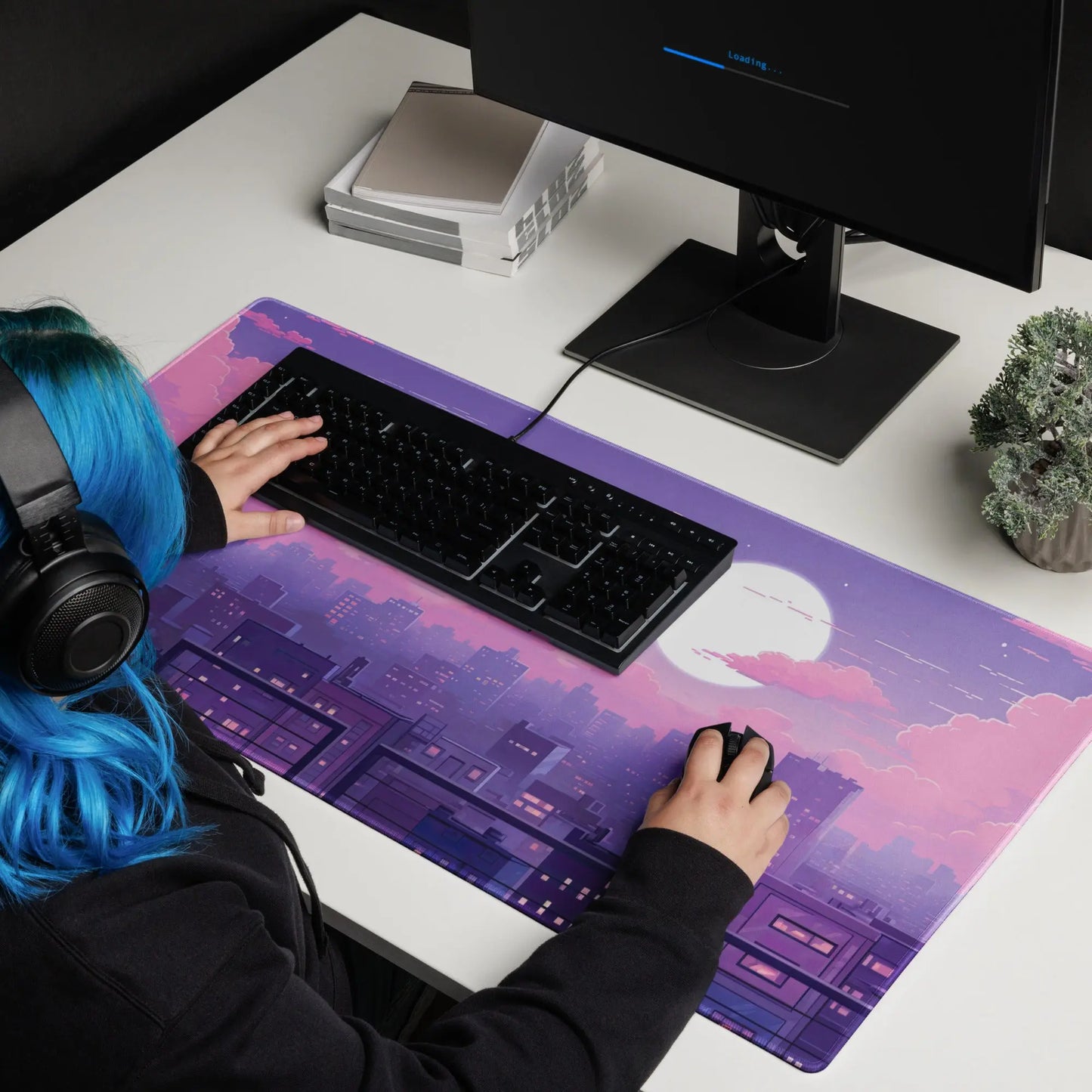 A girl sitting at a gaming desk mat with a purple and pink cityscape on it.