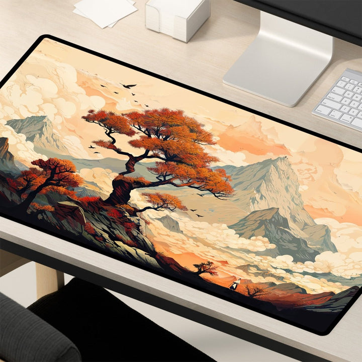 Home Decor - A desk showcasing the Japanese Desk Mat – a large mouse pad with a Japanese art - inspired design perfect for office and gaming. The mat features a vibrant artistic landscape, highlighting a prominent tree with orange foliage, distant mountains, and scattered clouds. Adjacent to the mat are a keyboard and monitor, creating an ideal workspace setting. - Kaladyn Designs