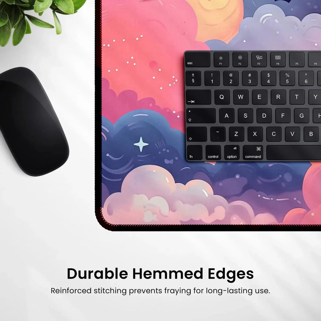 A mouse and a keyboard rest on a vibrant Kawaii Anime Desk Mat – Pastel Pink Night Sky Mouse Pad & Gaming Mat, which showcases a charming pastel pink night sky design adorned with clouds. The non-slip mat features reinforced hemmed edges, providing durable stitching that prevents fraying for extended longevity. Text at the bottom reads: "Durable Hemmed Edges - Reinforced stitching prevents fraying for long-lasting use.