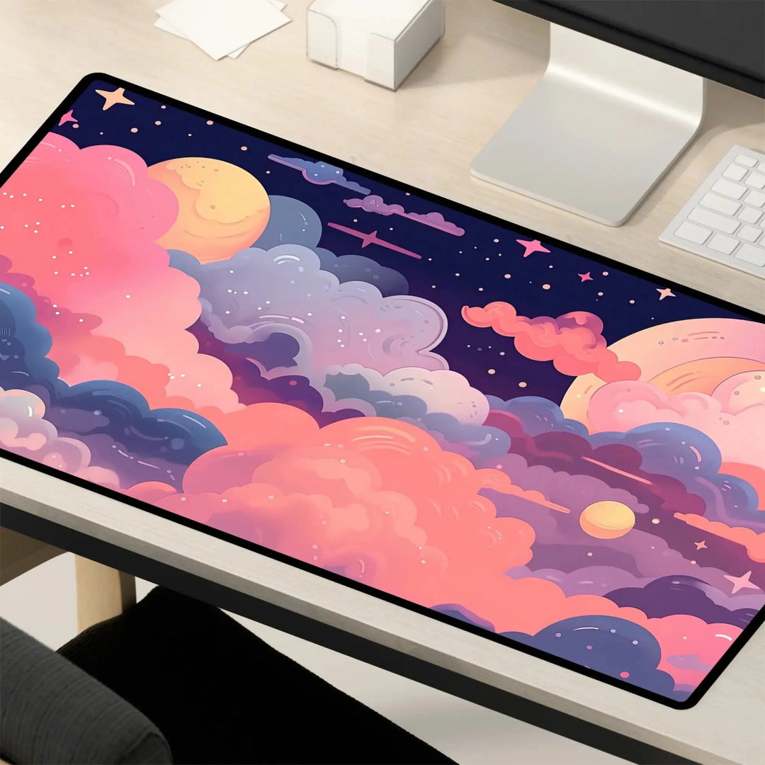 A vibrant Kawaii Anime Desk Mat – Pastel Pink Night Sky Mouse Pad & Gaming Mat adorns a wooden desk, showcasing a vivid pastel pink night sky with pink, purple, and blue clouds, starry skies, and celestial bodies. The non-slip mat is accompanied by a monitor, keyboard, and other office items.