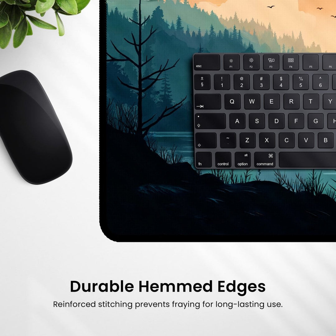 Home Decor - A computer keyboard and mouse sit on the Mountain Desk Mat – Large Nature - Inspired Mouse Pad for Gaming & Office, featuring silhouettes of trees and water. Beneath the image, the text reads "Durable Hemmed Edges," highlighting its reinforced stitching. - Kaladyn Designs